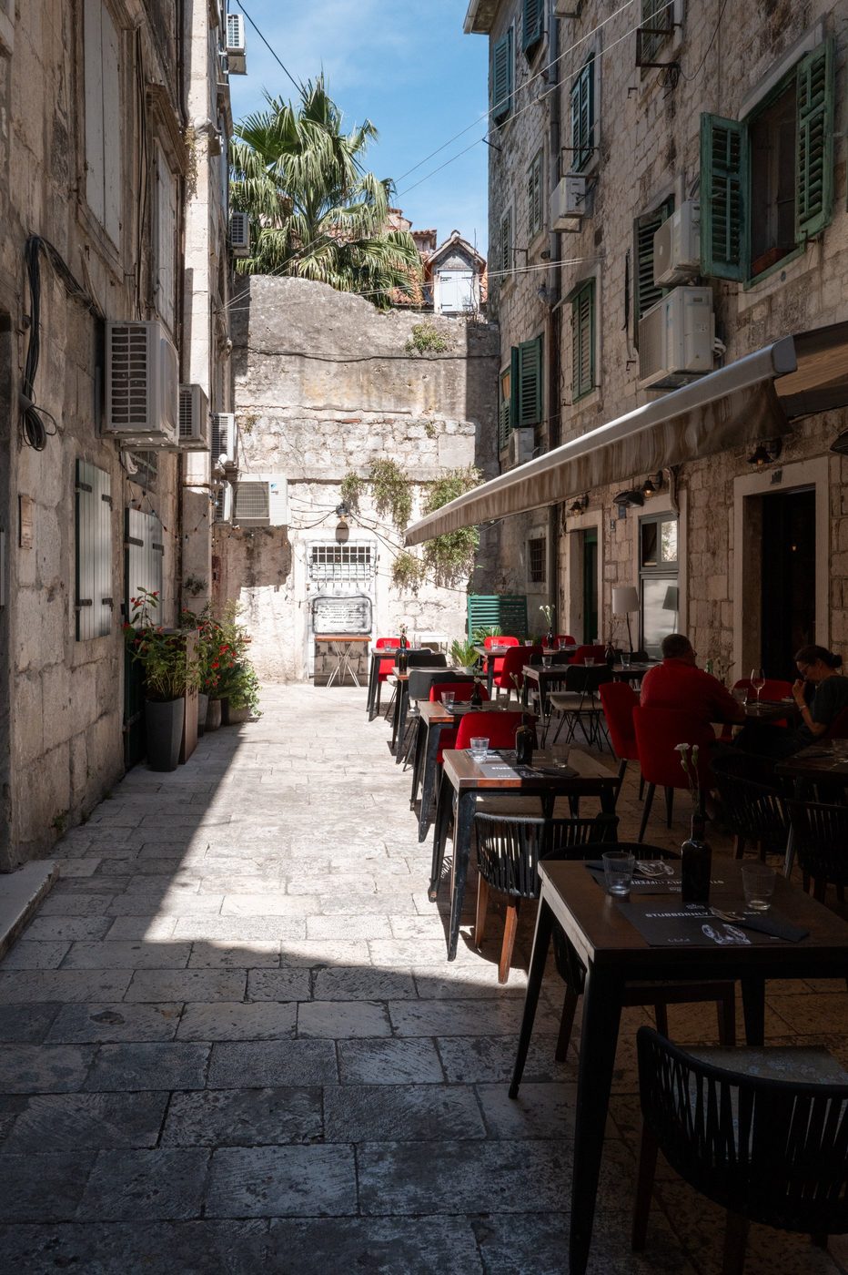 Lively terrace with red chairs beneath wall-mounted air conditioners, Split