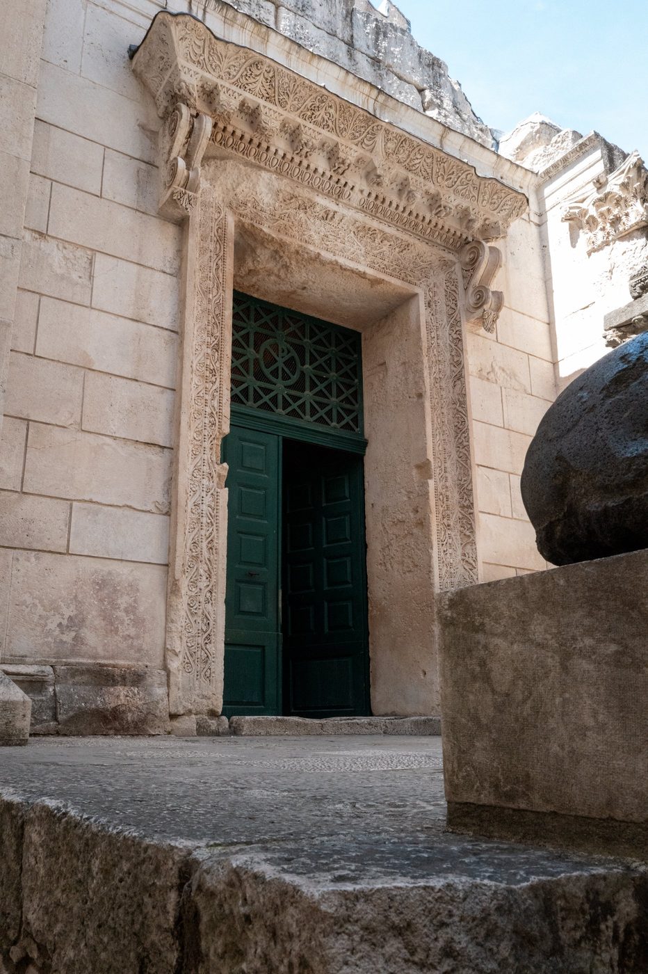Green gate set within the carved stone frame of a Roman temple, Split