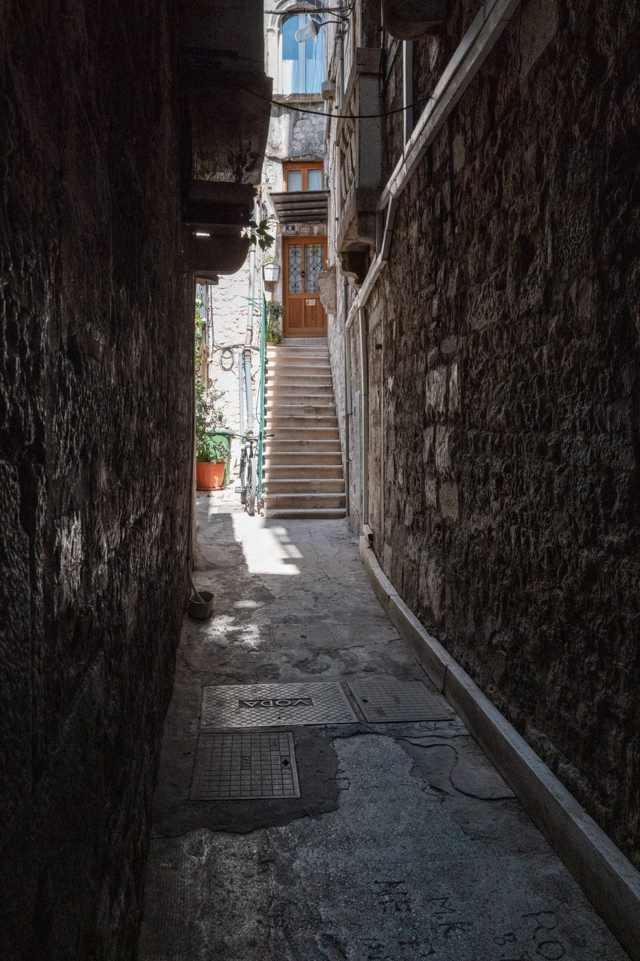 Wooden steps leading to a door at the end of a dark alley, Split