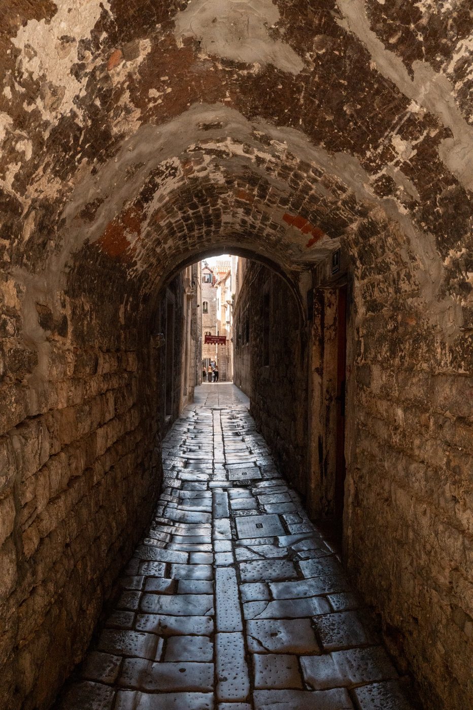 Vaulted stone passage leading to a sunlit alley, Split