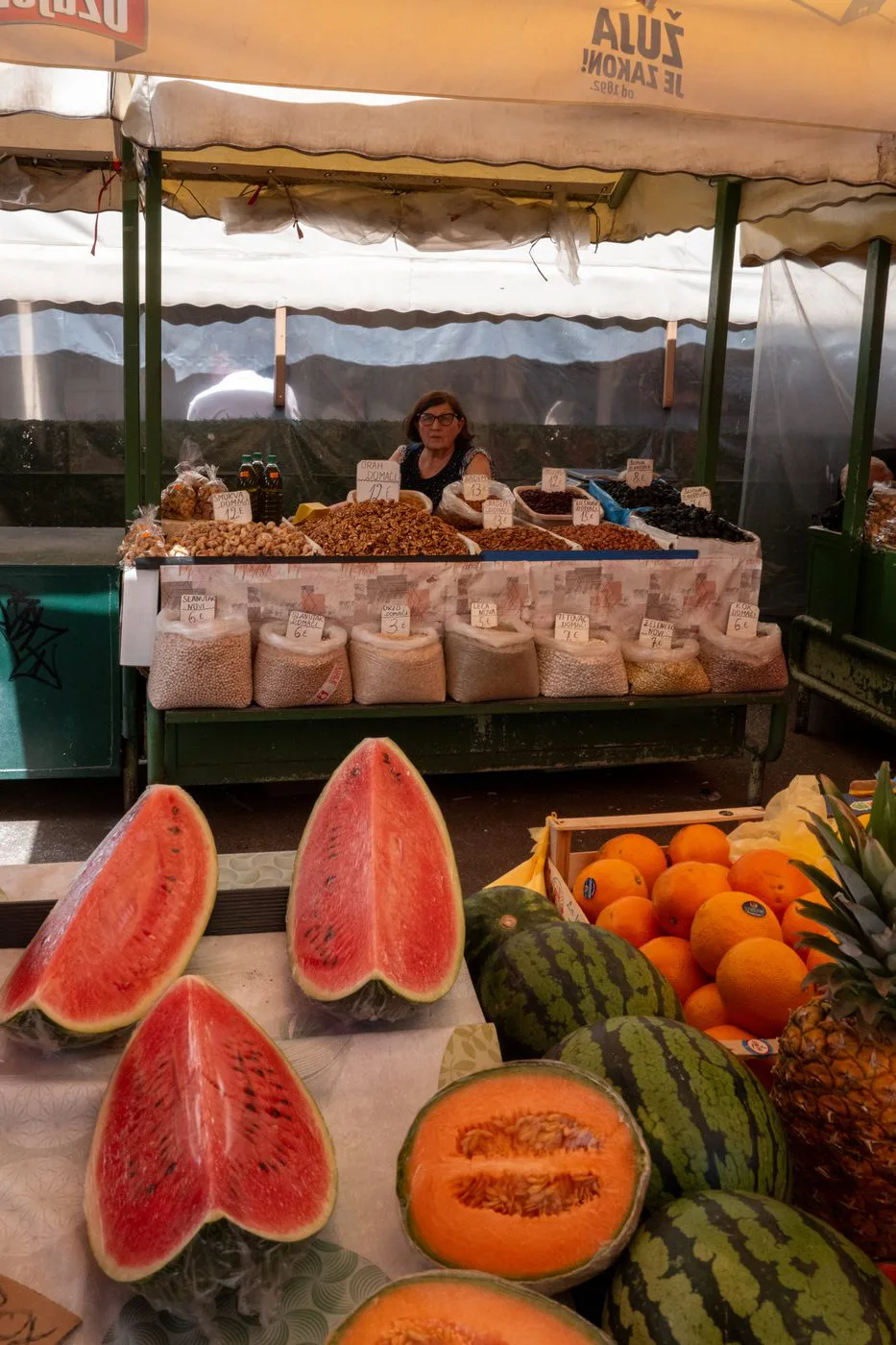 Marchande souriante entre les pasteques coupees et les caisses d'oranges du marche, Split