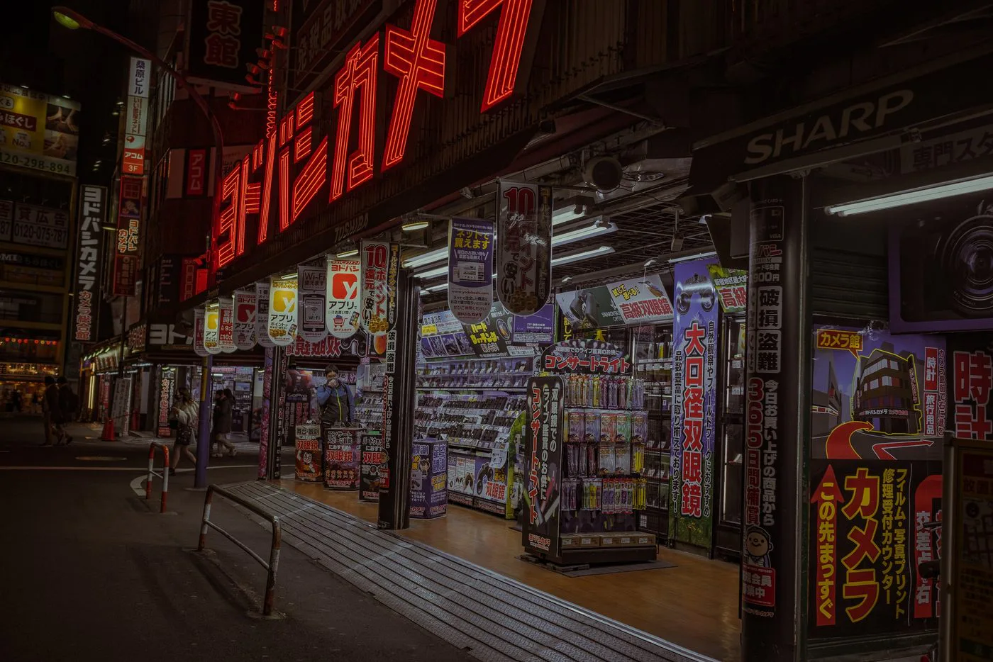 Neons rouges d'une boutique photo illuminant une rue nocturne deserte, Tokyo