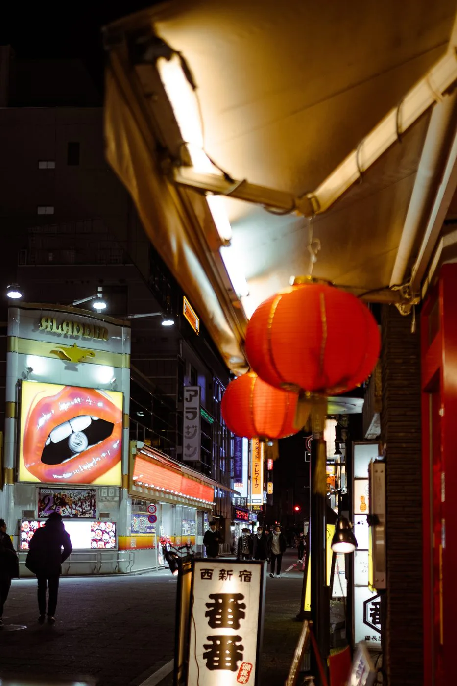 Quatre employes en costume et masque traversant devant une poissonnerie eclairee, Tokyo