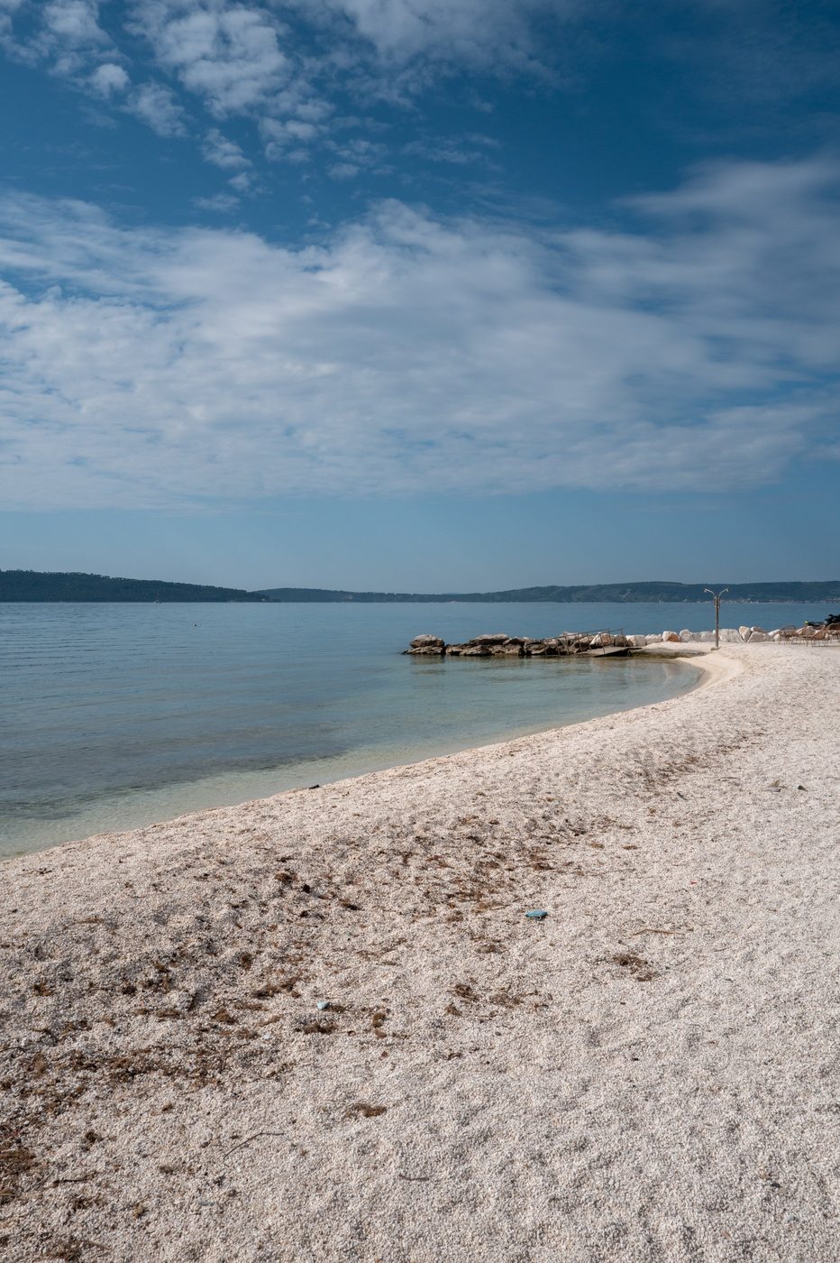 Deserted white pebble beach facing the calm bay, Trogir
