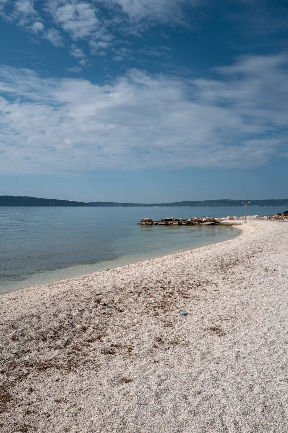 Plage de galets blancs déserte face à la baie calme, Trogir