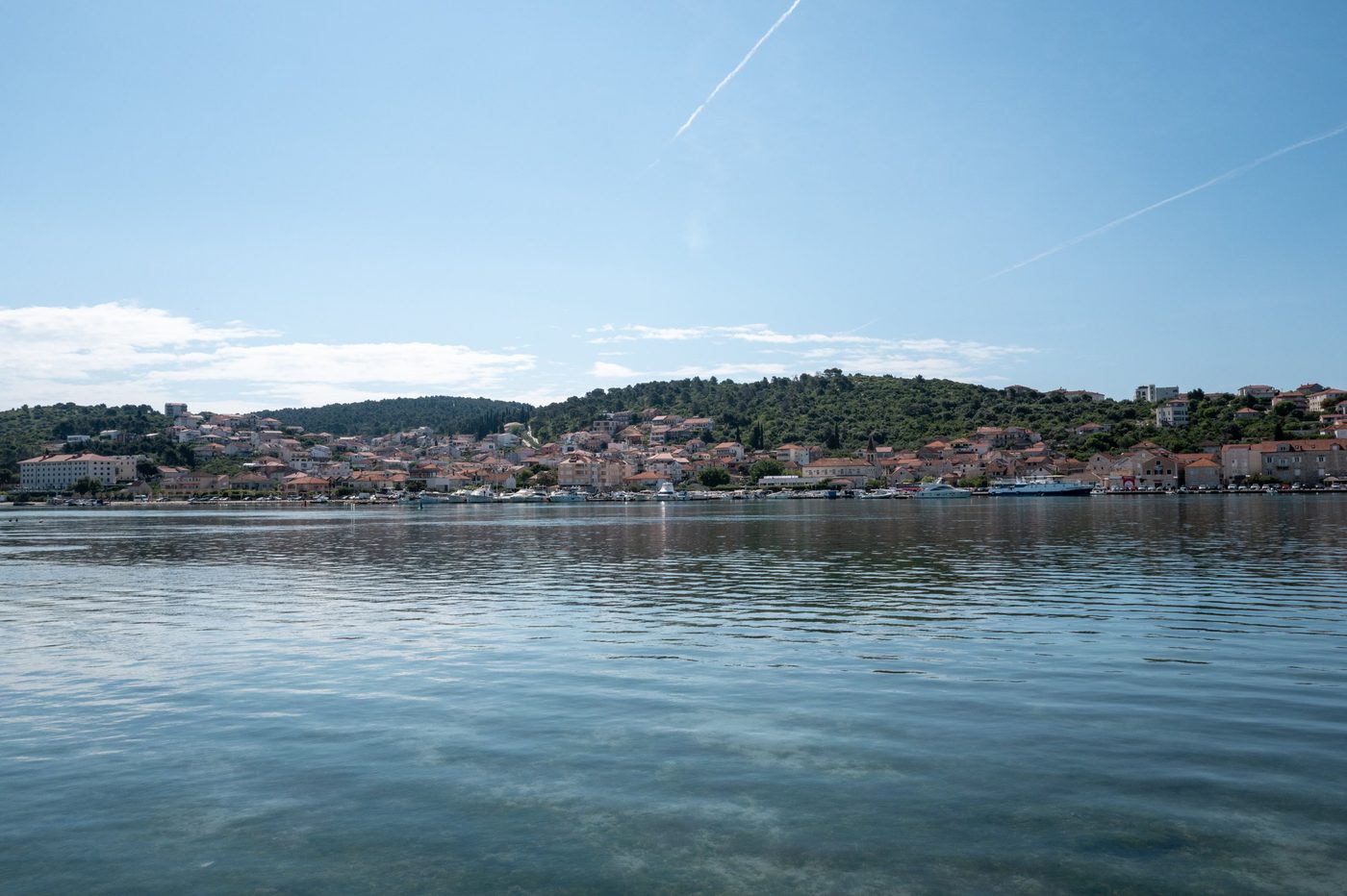 Wide view of the town nestled between a wooded hill and the sea, Trogir