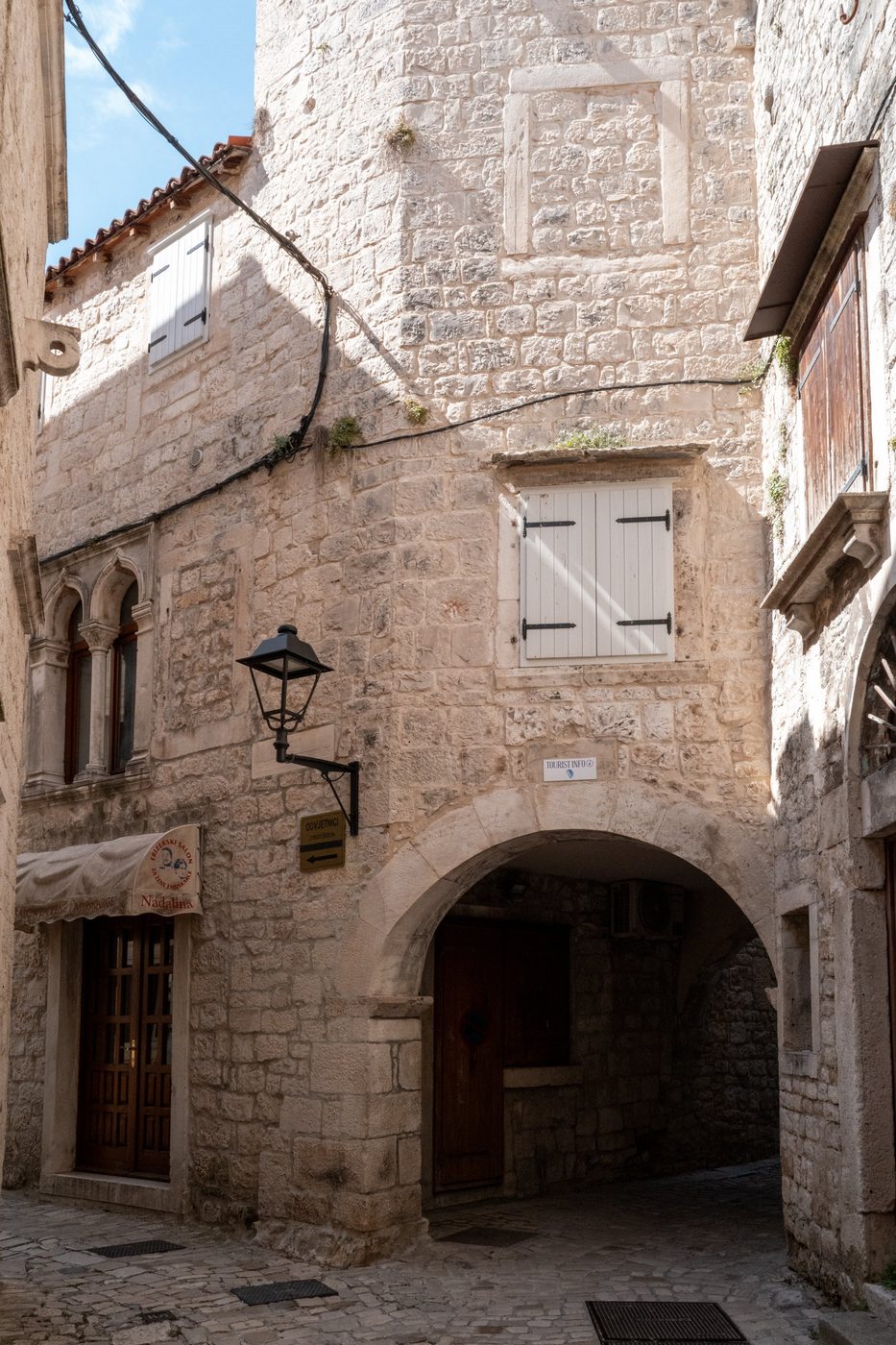 Stone street corner with a lantern and vaulted porch, Trogir