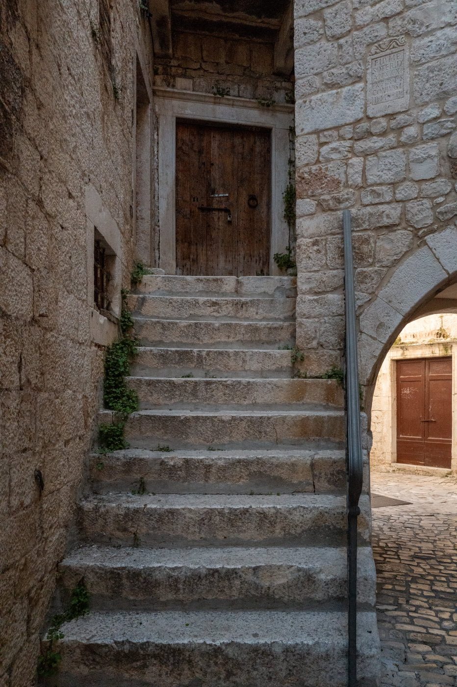 Worn stone staircase leading to an old wooden door, Trogir