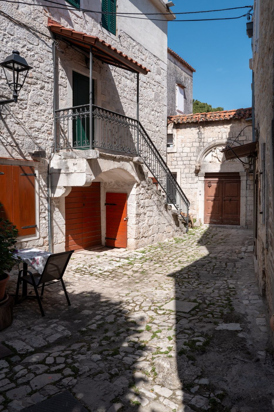 Inner courtyard with red doors and a wrought-iron balcony, Trogir