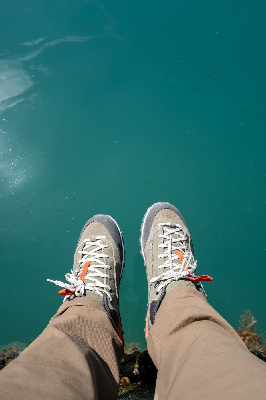 High-angle view of hiking shoes above the turquoise water, Trogir