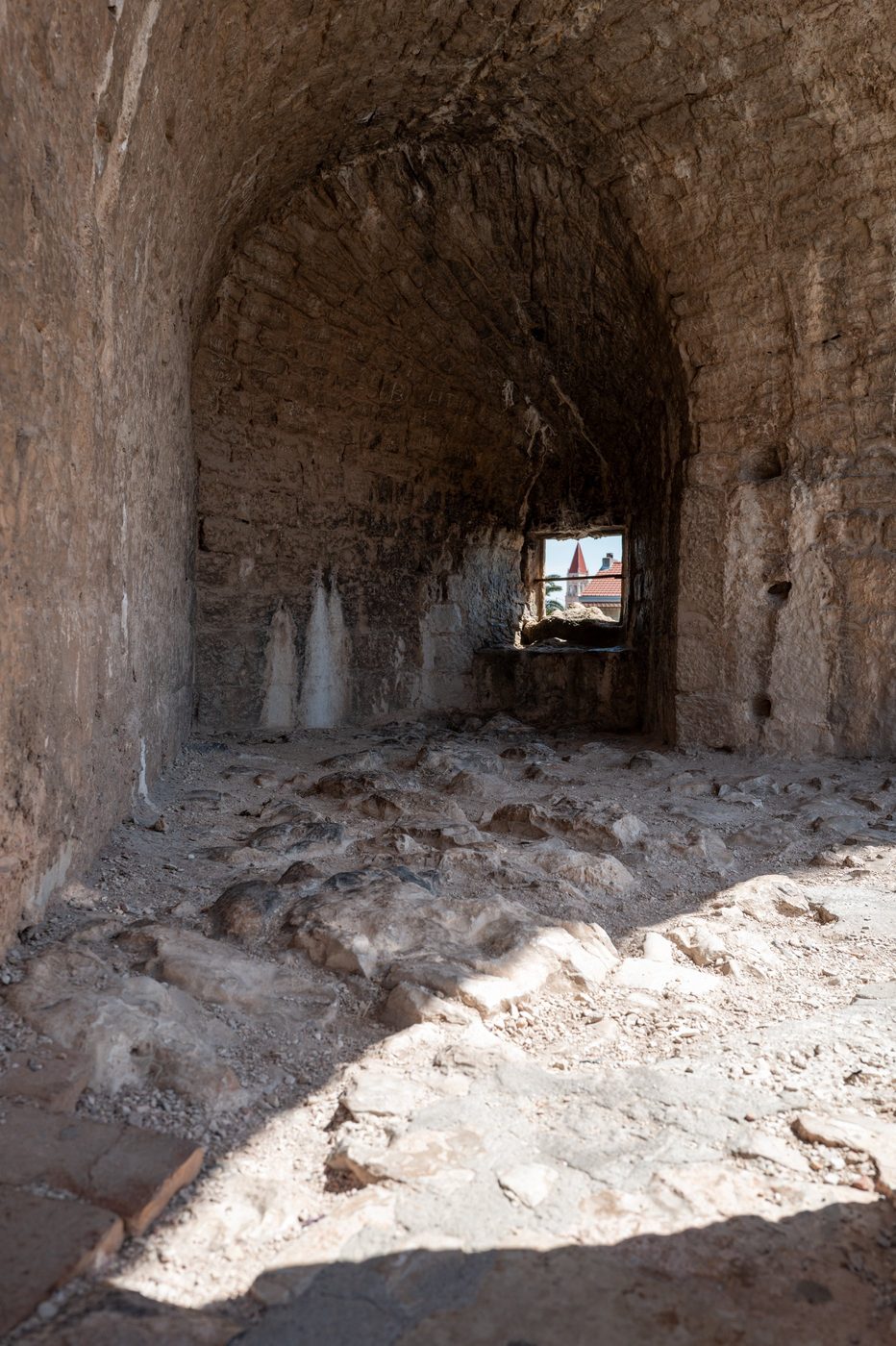 Vaulted hall of the fortress with a framed view of the bell tower, Trogir