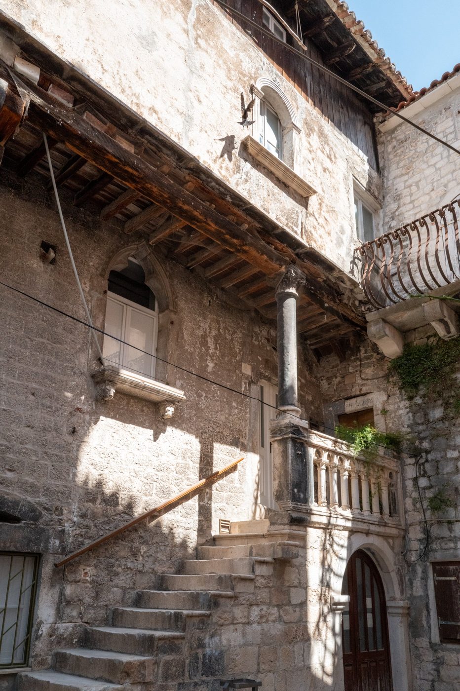 Gothic balcony with carved colonnette beneath an old wooden canopy, Trogir