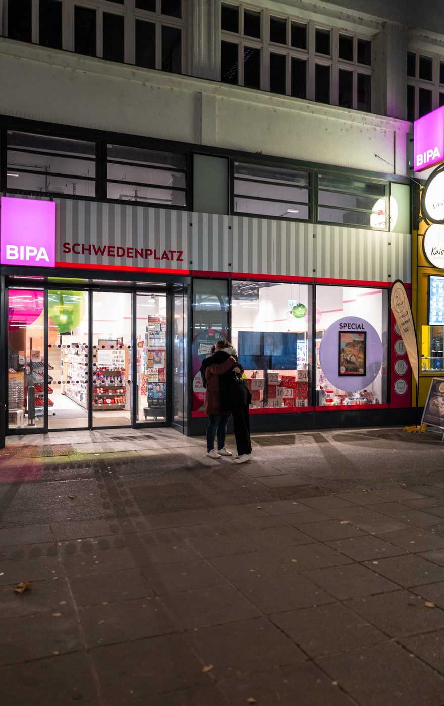 Couple embracing in front of an illuminated shop window, Vienna
