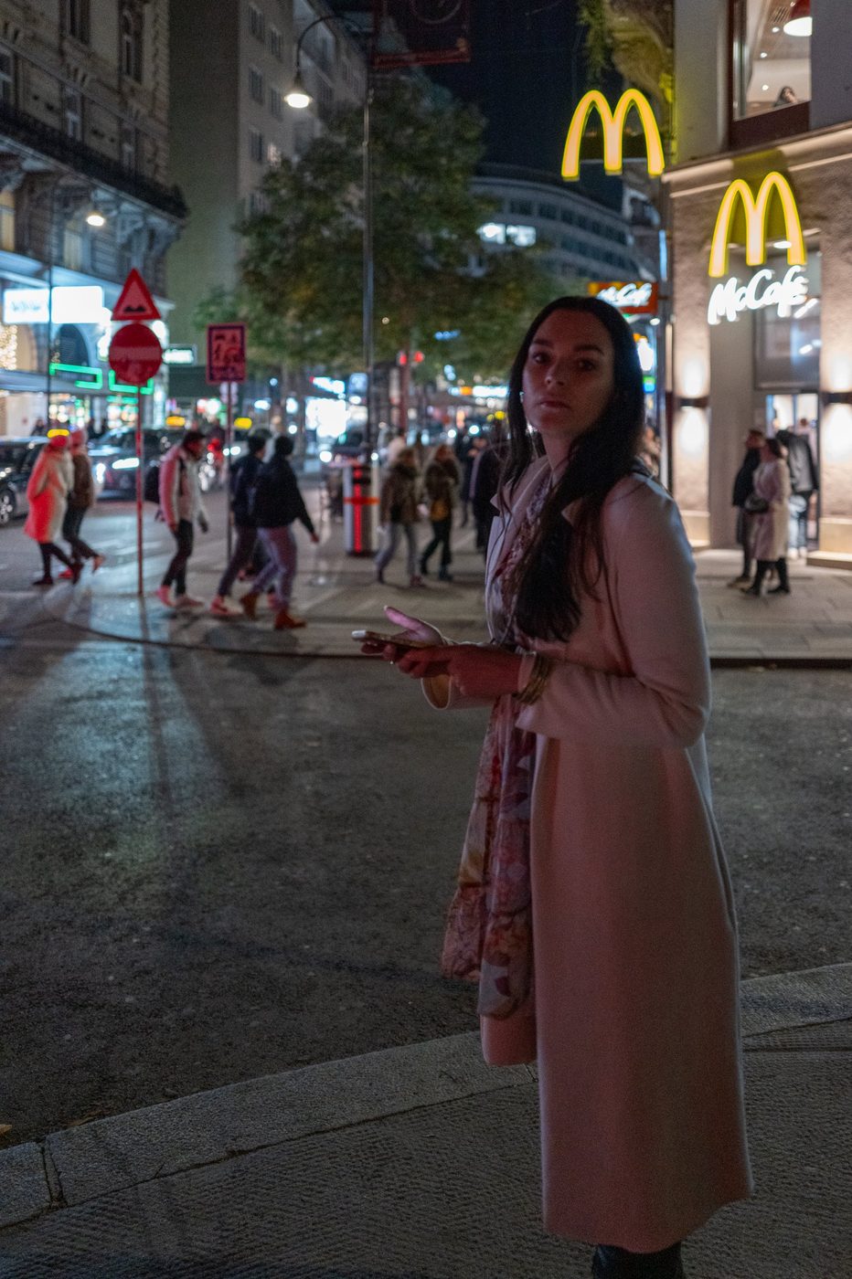Woman on the phone in front of the illuminated fast-food arches, Vienna