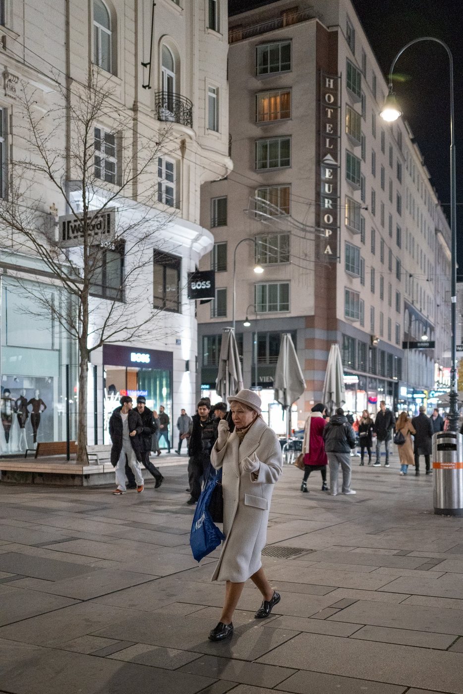Bundled-up woman walking past the Hotel Europa sign, Vienna
