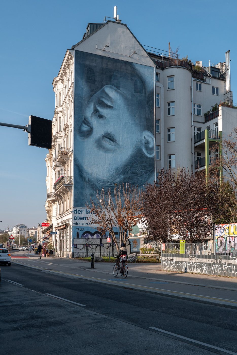 Cyclist passing in front of a monumental mural, Vienna