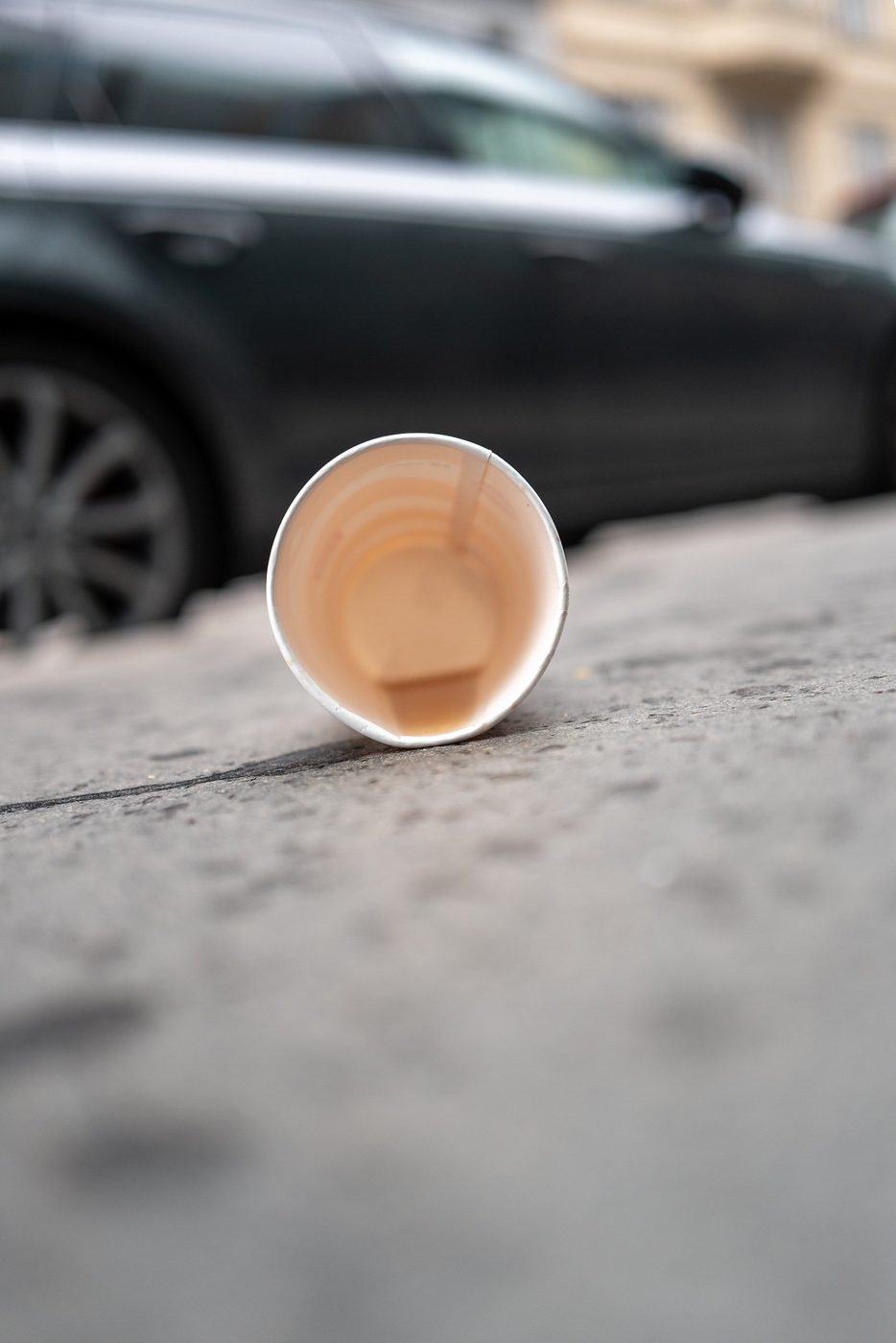 Coffee cup left on the sidewalk in front of a car, Vienna
