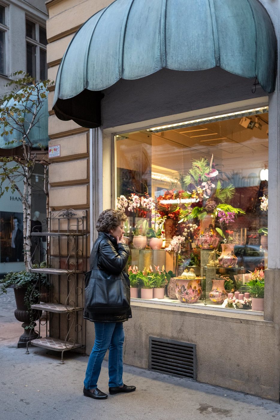 Woman smoking in front of a florist's flower-filled window, Vienna