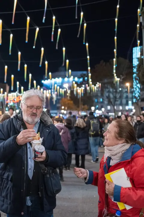 Homme mangeant et femme riant sous des guirlandes lumineuses le soir, Barcelone