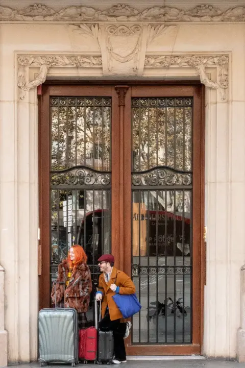 Couple avec des valises devant une grande porte ancienne en bois, Barcelone