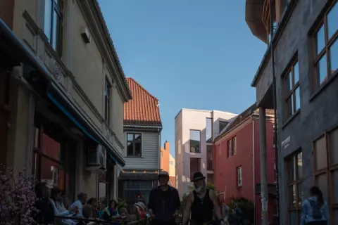 A backlit street, full terraces and two silhouettes, Bergen