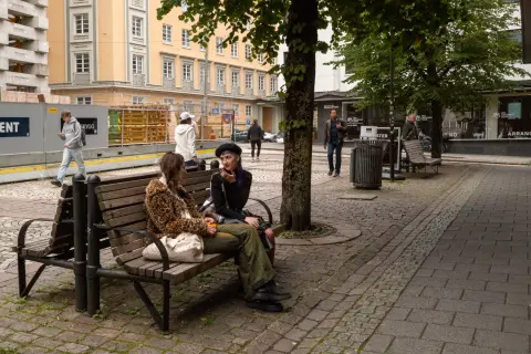 Two women chatting on a bench under the trees, Bergen