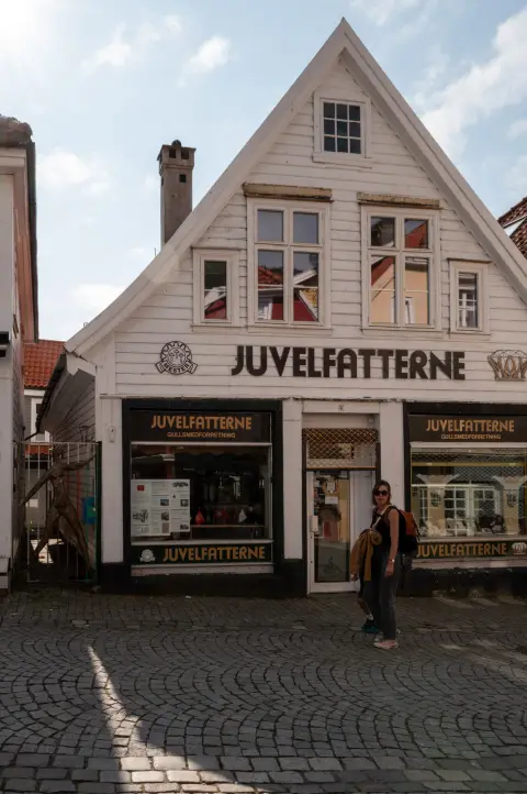 A white wooden house housing a jeweller, a woman passing in front, Bergen
