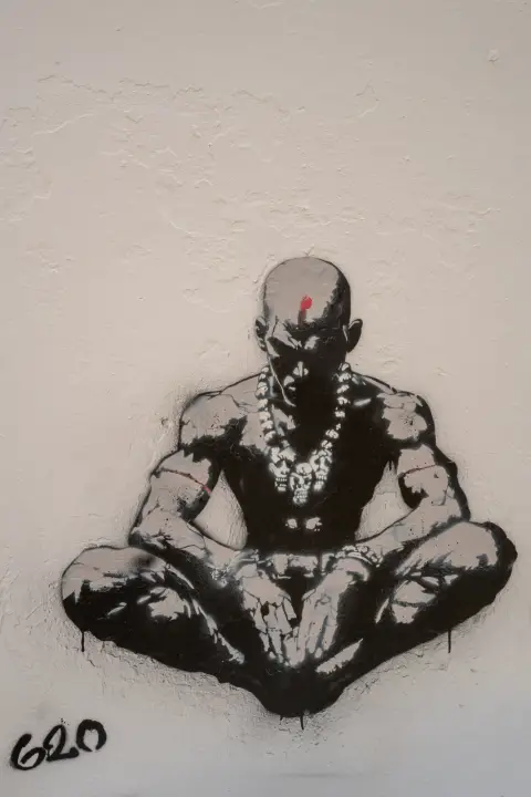 A stencil of a man meditating on a white wall, Bergen