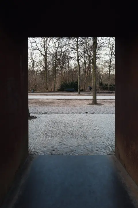 Encadrement de métal rouillé ouvrant sur une allée boisée pavée, Berlin