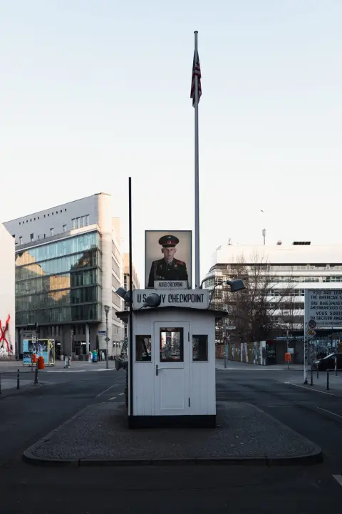 Guérite de Checkpoint Charlie encadrée par le drapeau américain et un portrait de soldat, Berlin
