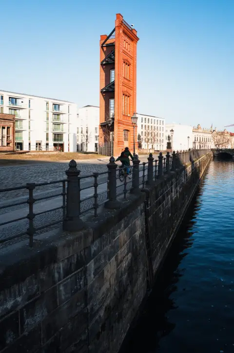 Tour de brique rouge au bord d'un canal, un cycliste longe le quai, Berlin
