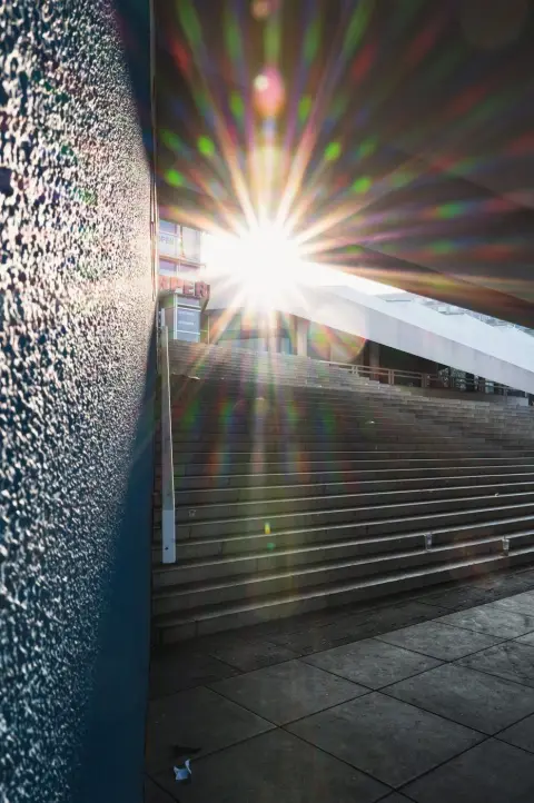 Éclat de soleil filtrant entre deux façades au-dessus d'un escalier, Berlin
