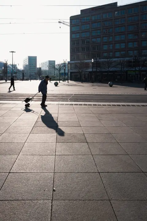Homme tirant un chariot à roulettes sur la place Alexanderplatz, Berlin
