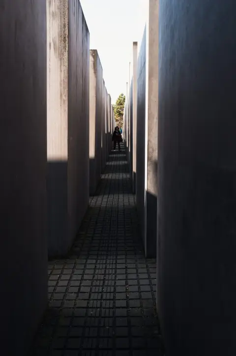 Silhouette isolée au bout d'un couloir entre les stèles du mémorial, Berlin