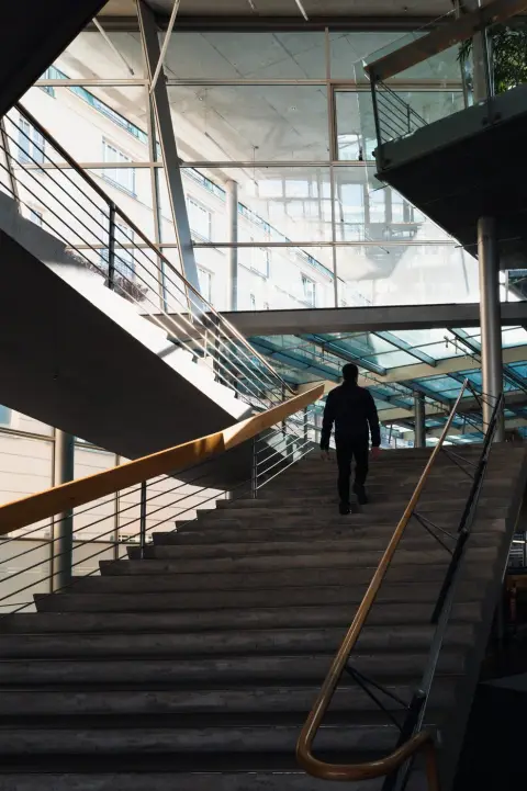 Homme montant un escalier de béton sous une verrière architecturale, Berlin