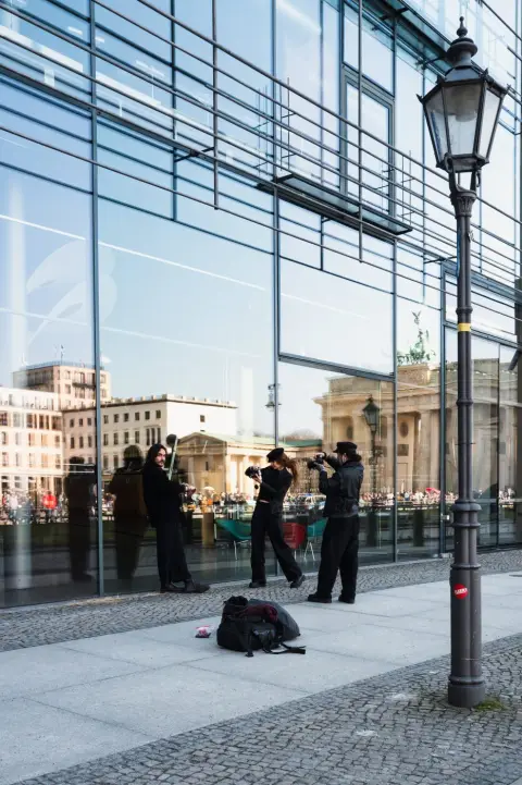 Musiciens de rue reflétés dans une façade vitrée près de la porte de Brandebourg, Berlin