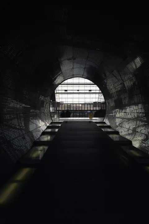 Tunnel métallique nervuré menant vers une sortie vitrée lumineuse, Berlin