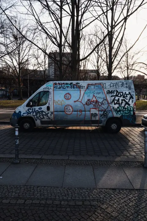 Camionnette blanche entièrement recouverte de graffitis, garée sous les arbres, Berlin