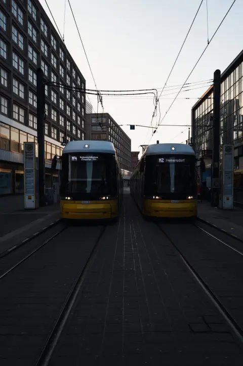 Deux tramways jaunes se faisant face symétriquement entre les immeubles, Berlin