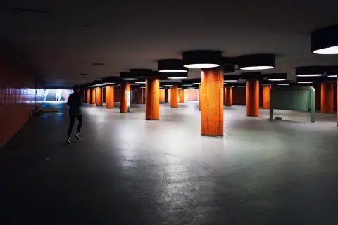 Coureur solitaire traversant un hall souterrain aux colonnes orange, Berlin