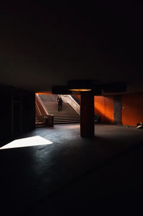 Homme éclairé par un rai de lumière au pied d'un escalier souterrain, Berlin