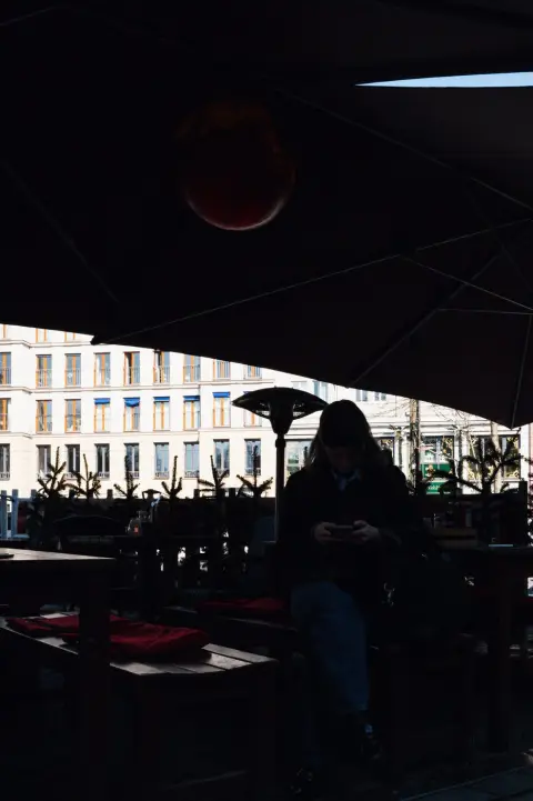 Silhouette d'une passante sous un parasol, plongée dans son téléphone, Berlin