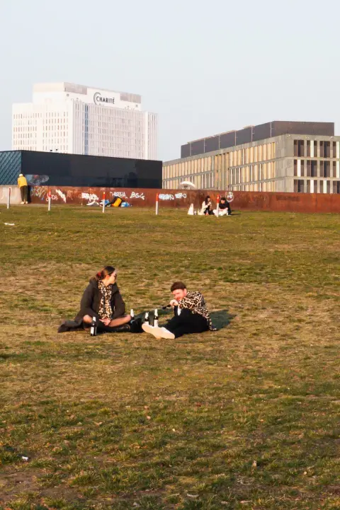 Couple pique-niquant sur une pelouse face à la tour de l'hôpital Charité, Berlin