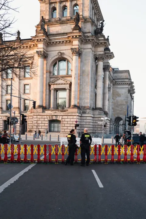Deux policiers postés derrière une barrière rouge et jaune devant le Reichstag, Berlin