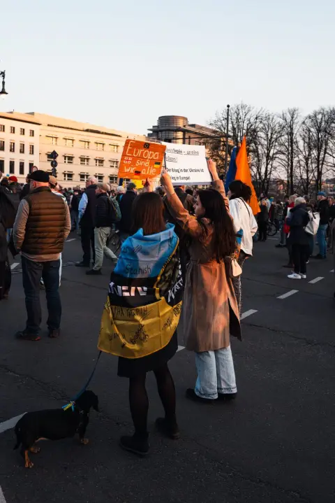 Manifestantes tenant des pancartes de solidarité, chien en laisse au premier plan, Berlin