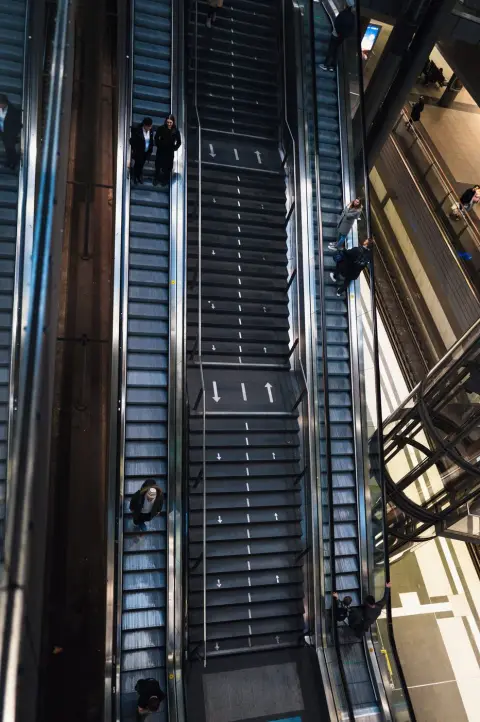 Vue plongeante en diagonale sur des escalators croisés et leurs passagers, Berlin