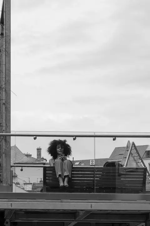 Une passante aux cheveux boucles assise sur un banc de toit-terrasse, Budapest