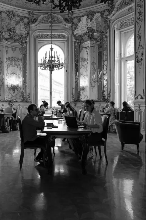 Etudiants installes a une table sous un lustre en cristal, salle baroque, Budapest