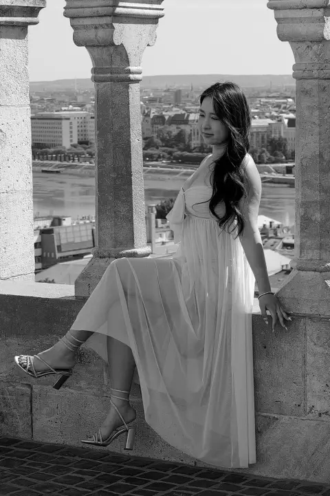 Une passante en robe vaporeuse assise entre deux colonnes du Bastion, Budapest