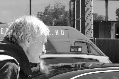 Portrait de profil d'un homme age fumant la pipe pres d'une voiture, Budapest